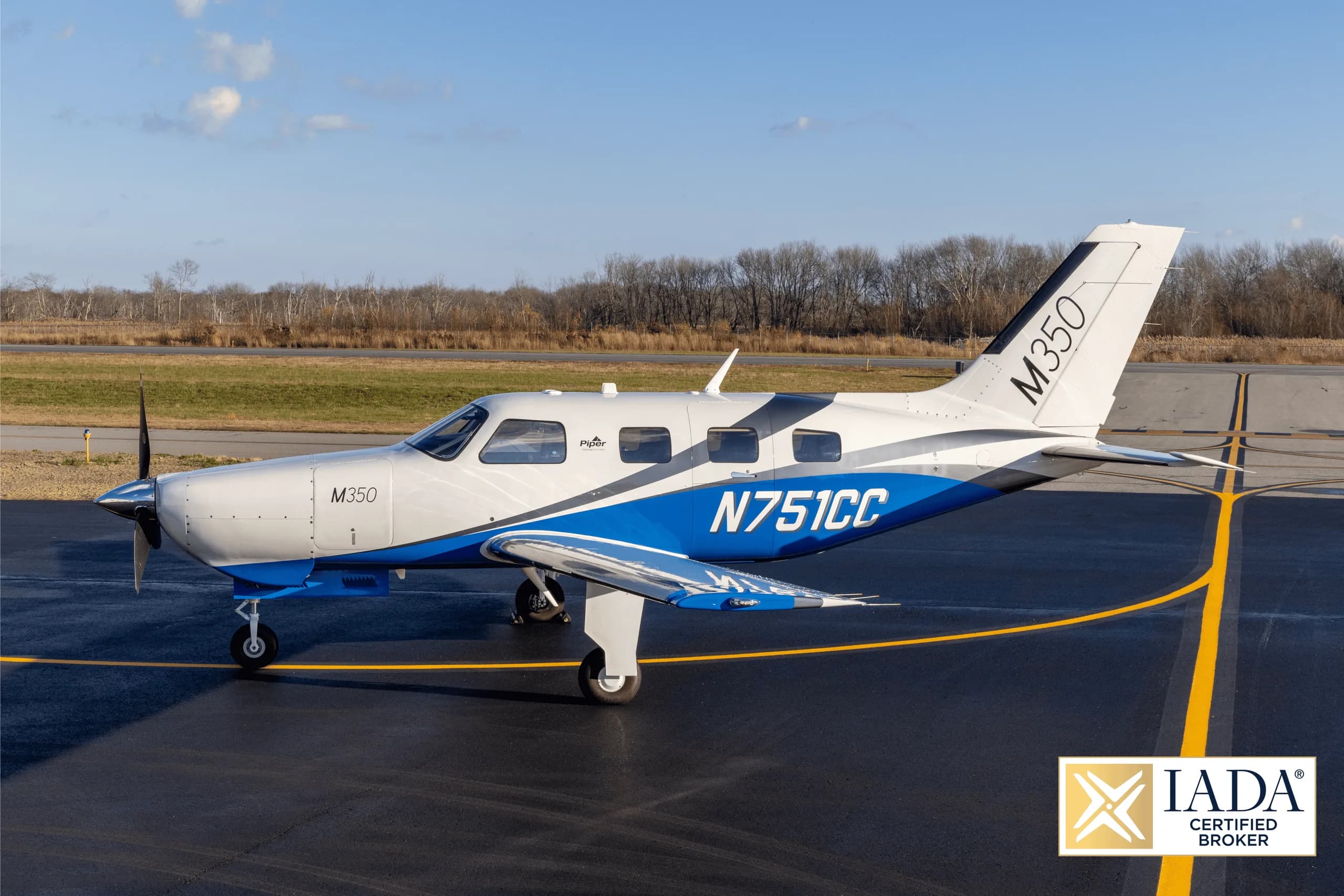 A Piper M350 aircraft, registration N751CC, with a white and blue paint scheme, parked on an airfield.