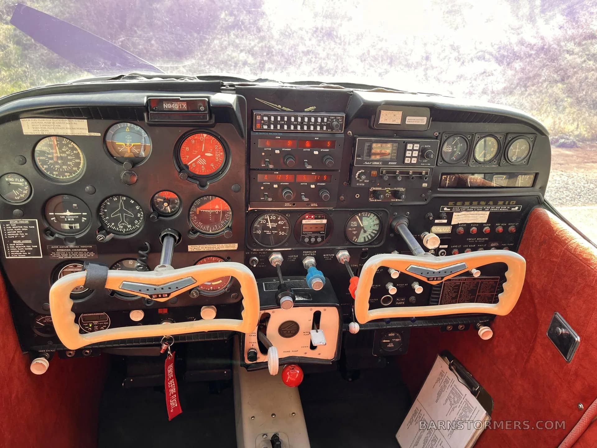 The cockpit of a Cessna 182 aircraft, showing the instrument panel, avionics, and control yokes.