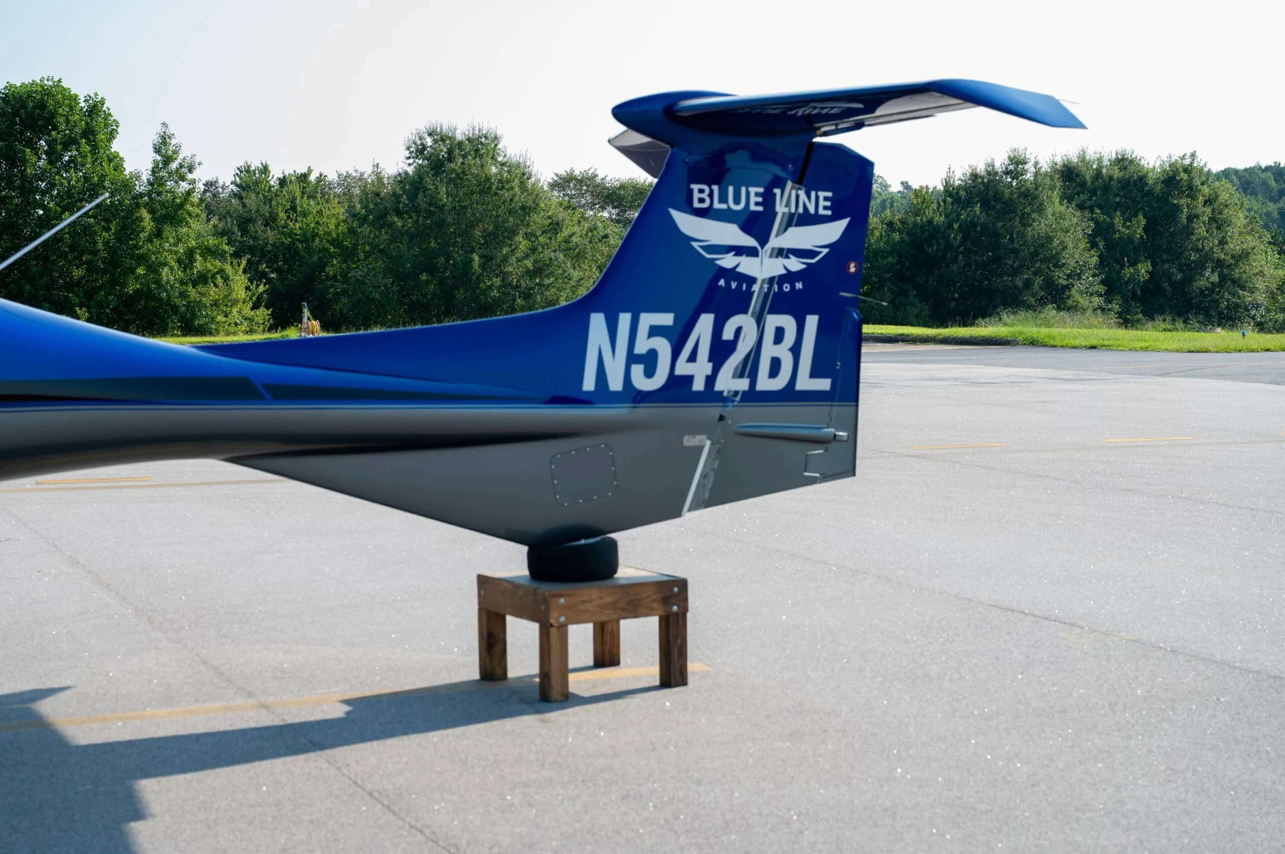 Close-up of the tail of a blue and grey Diamond DA42 aircraft showing the N-number and "Blue Line Aviation" logo.