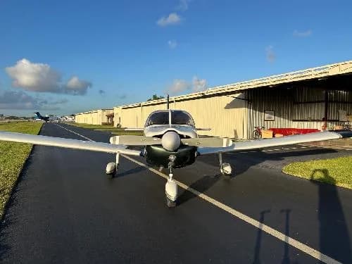 Front view of Piper PA-28-181 Archer II aircraft N1435T on the tarmac with hangars in the background.
