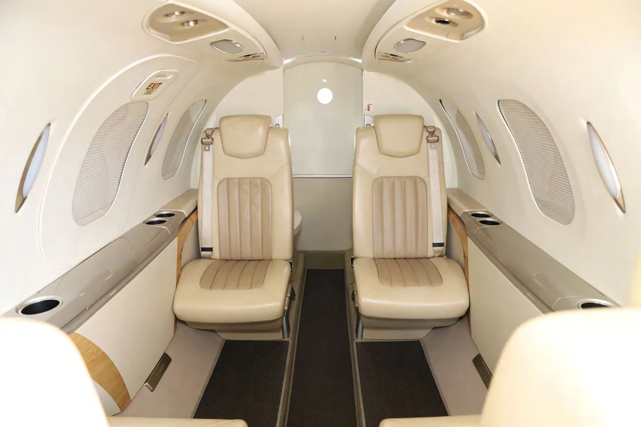 The interior cabin of a HondaJet Elite S, showing two tan leather seats facing rearward towards the lavatory.