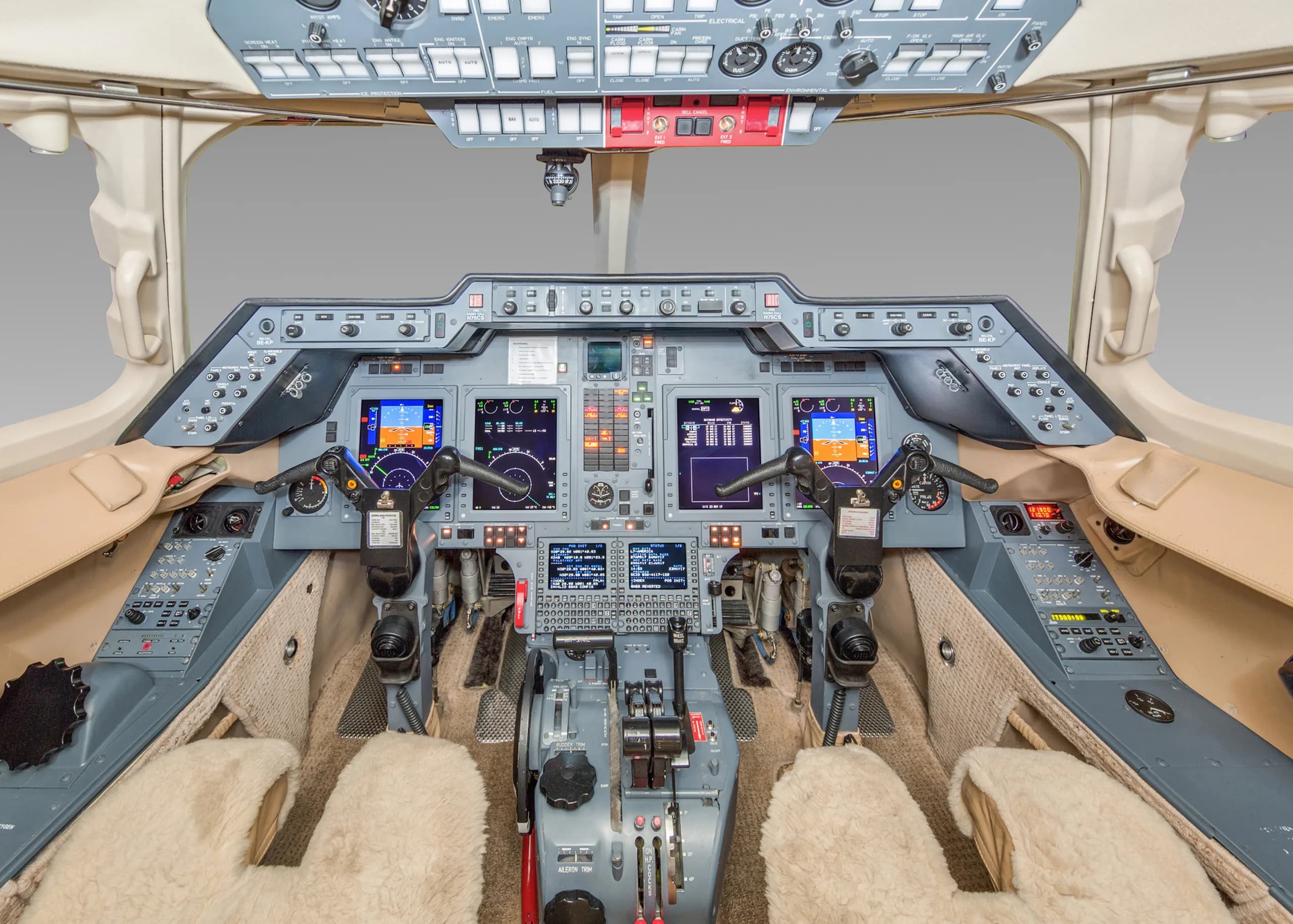 The cockpit of a private jet, showing the instrument panel, multiple display screens, and control yokes.
