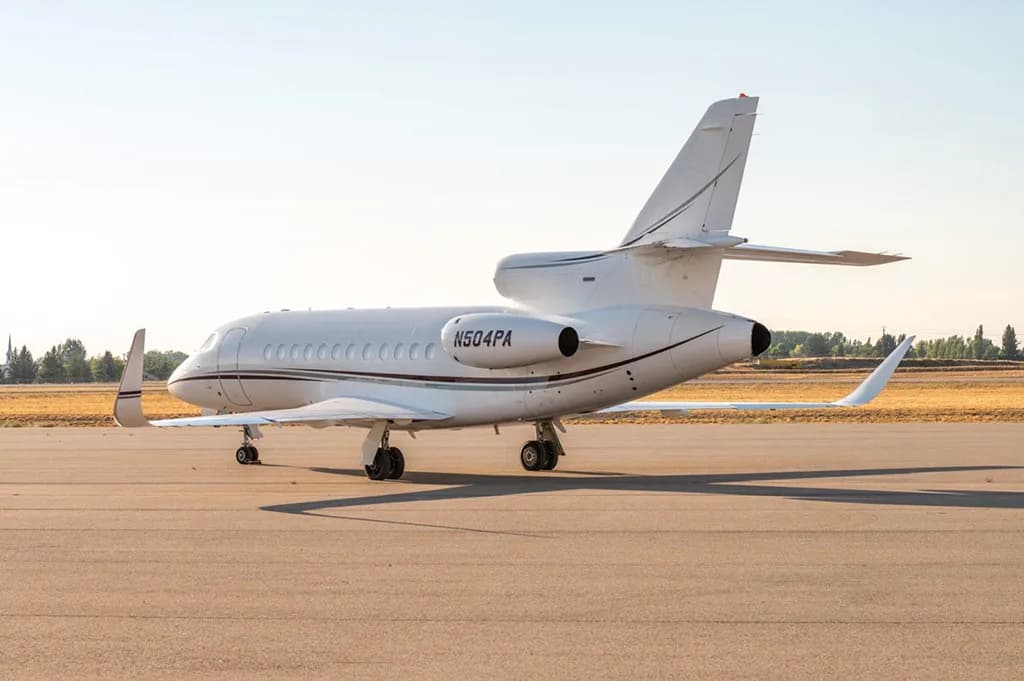 A rear-side view of the Dassault Falcon 900EX business jet, registration N504PA, parked on the tarmac.