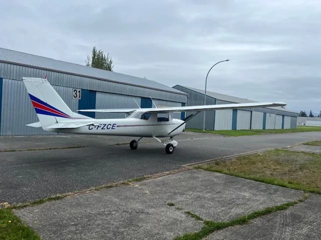Side view of the C-FZCE Cessna aircraft parked on the tarmac in front of a hangar.