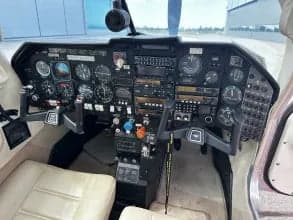 Full view of the aircraft's cockpit with a black instrument panel and cream-colored seats.