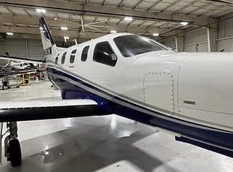 Close up of the front of a white and blue aircraft in a hangar.