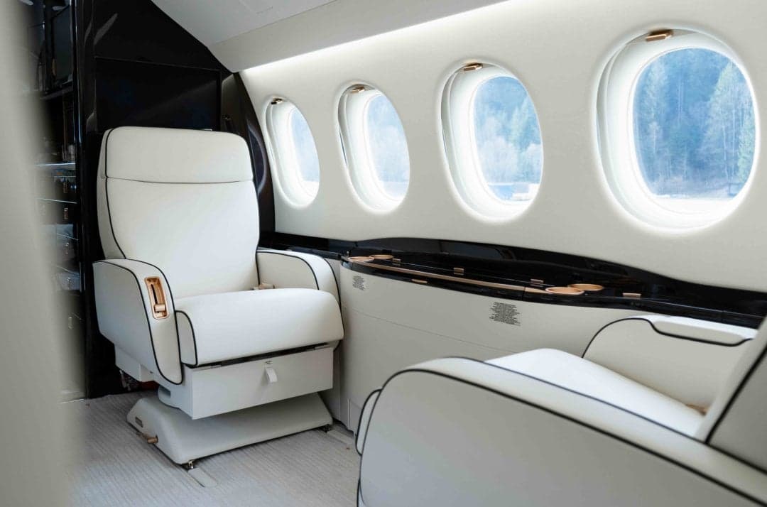 A close-up of the aircraft's interior with white leather seats and windows.