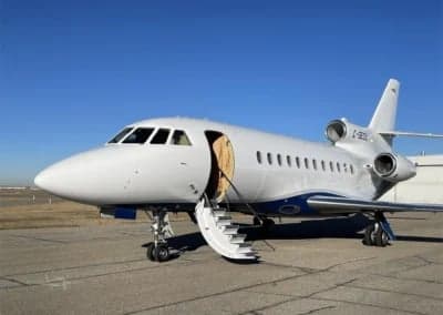 A white and blue Dassault Falcon 900EX, registration C-GEOS, with the entry stairs extended.