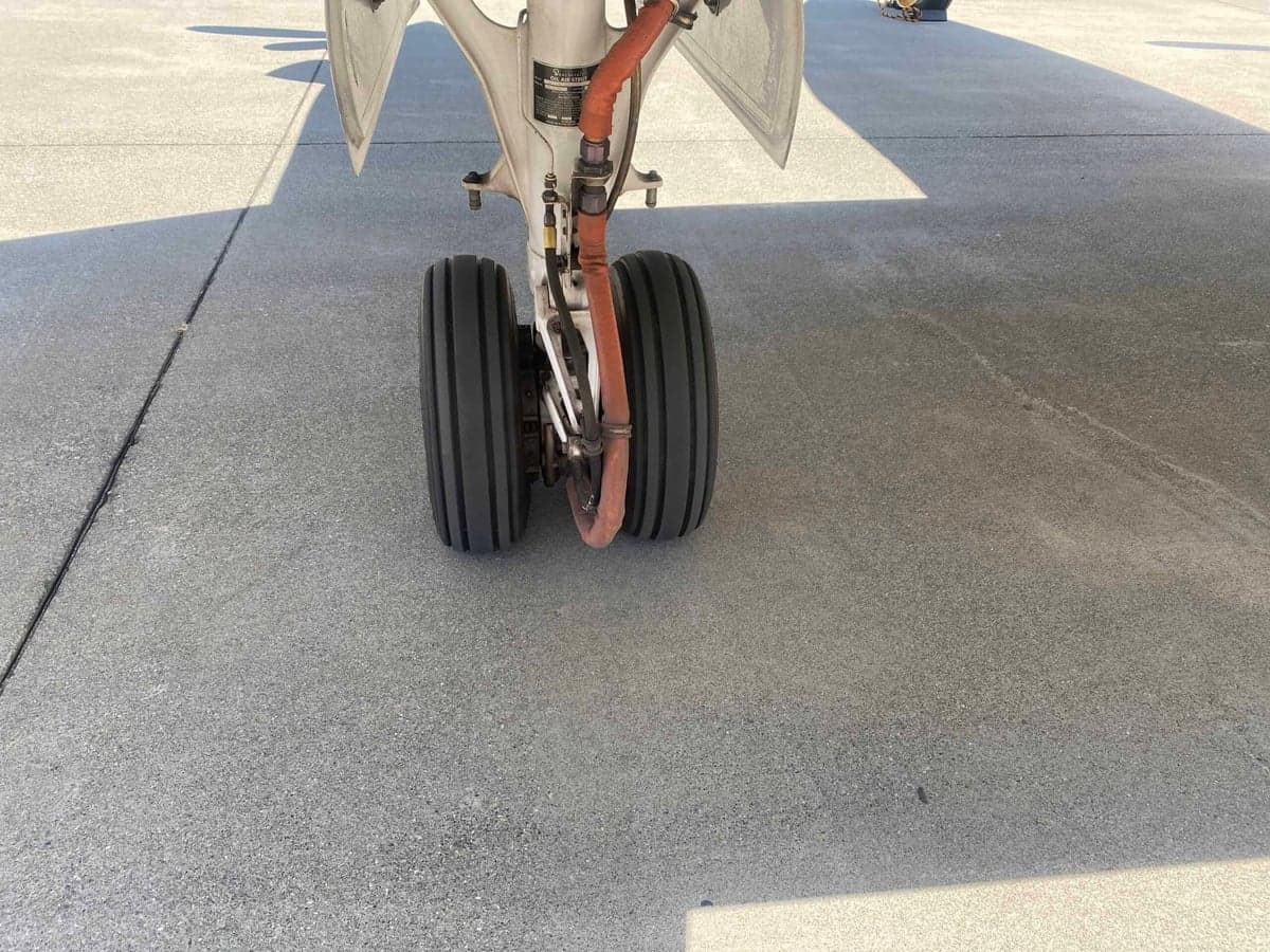 A close-up view of the main landing gear wheels of the aircraft on an asphalt surface.