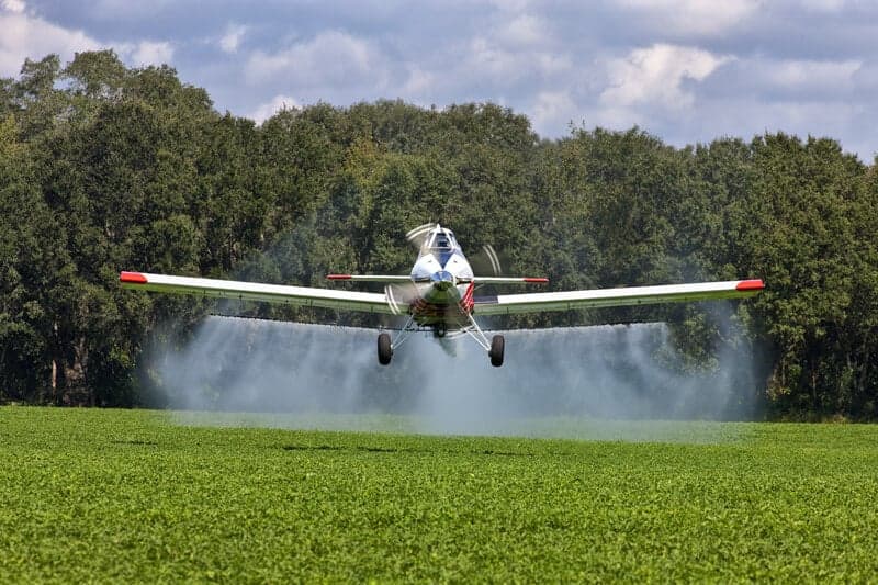 A Thrush aircraft sprays a field of crops.