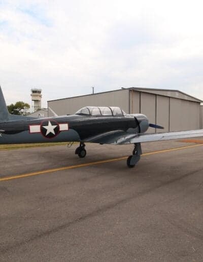 Side view of the gray N700YK aircraft parked on the tarmac near a hangar.
