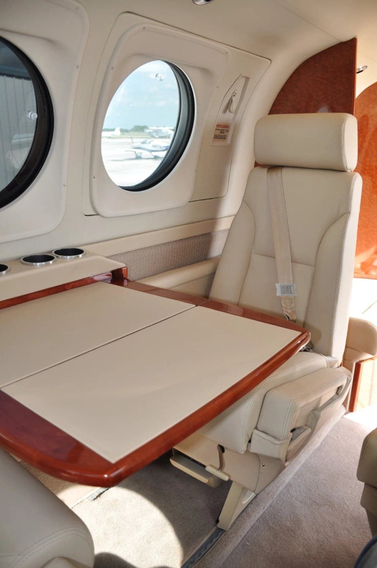 Interior view of the aircraft cabin with a table and cream-colored leather seats.