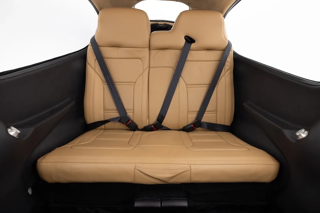 A view of the tan leather rear seats with seatbelts in the aircraft cabin.