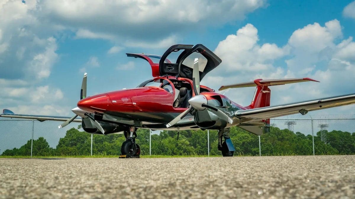 Diamond DA62 with red paint scheme and open gull-wing doors on the tarmac.