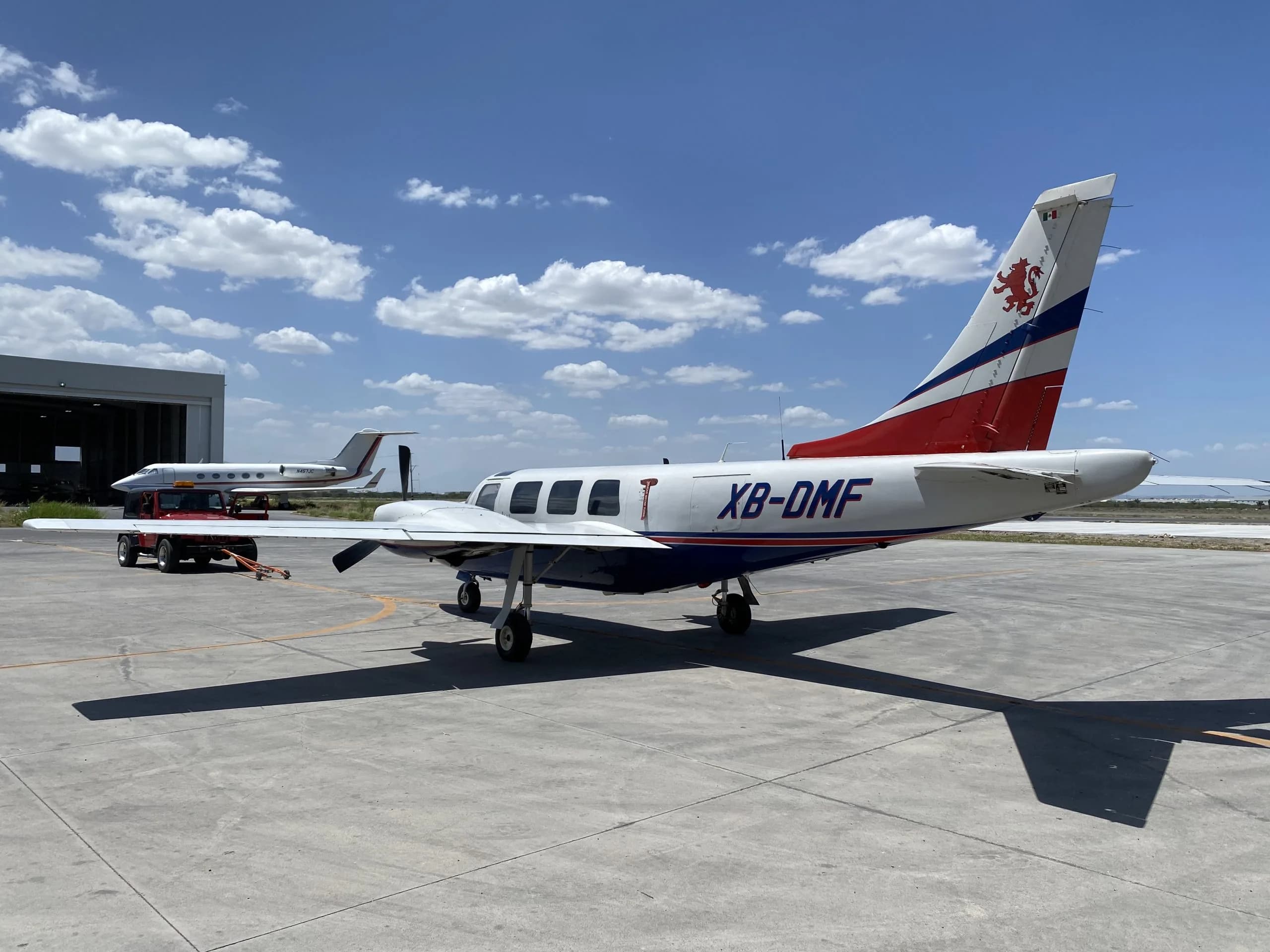 Rear side view of the XB-DMF aircraft parked on the tarmac.