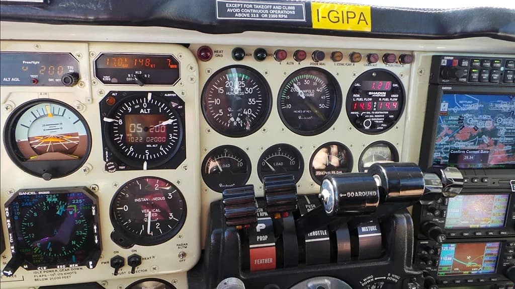 Close-up view of an aircraft cockpit instrument panel showing engine controls, gauges, and navigation screens.