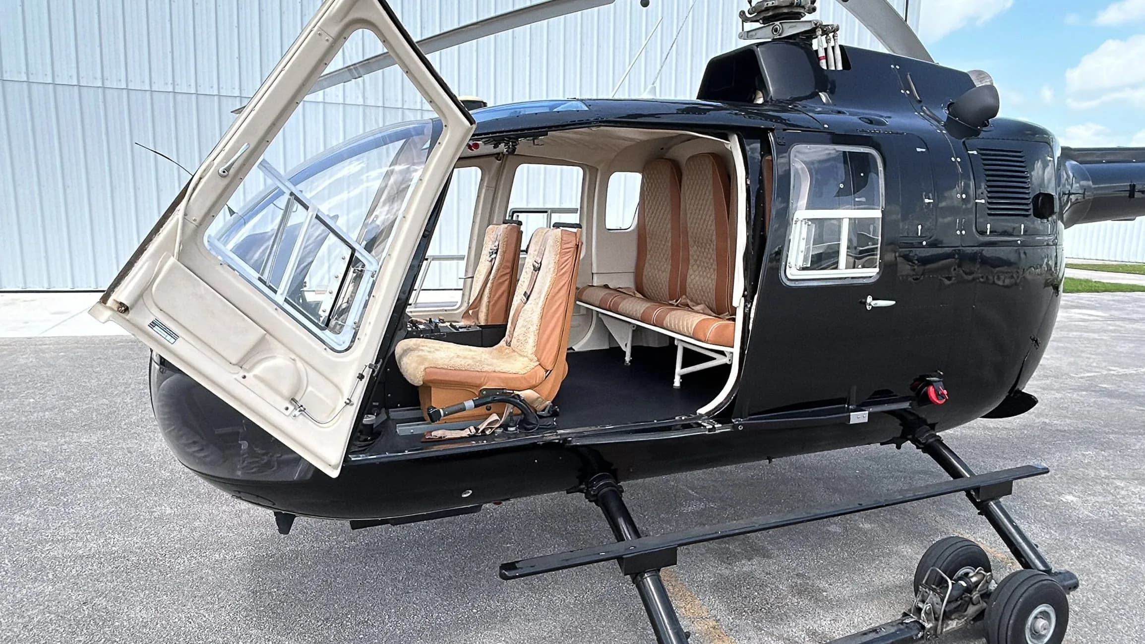 Close-up of the helicopter's cabin interior with tan seats and an open door.