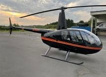 Side view of a Robinson R44 Raven II helicopter on the tarmac.