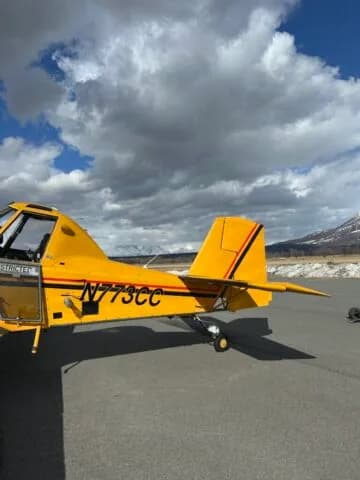 Close-up side view of the rear fuselage and tail of a yellow crop duster aircraft with registration N773CC.