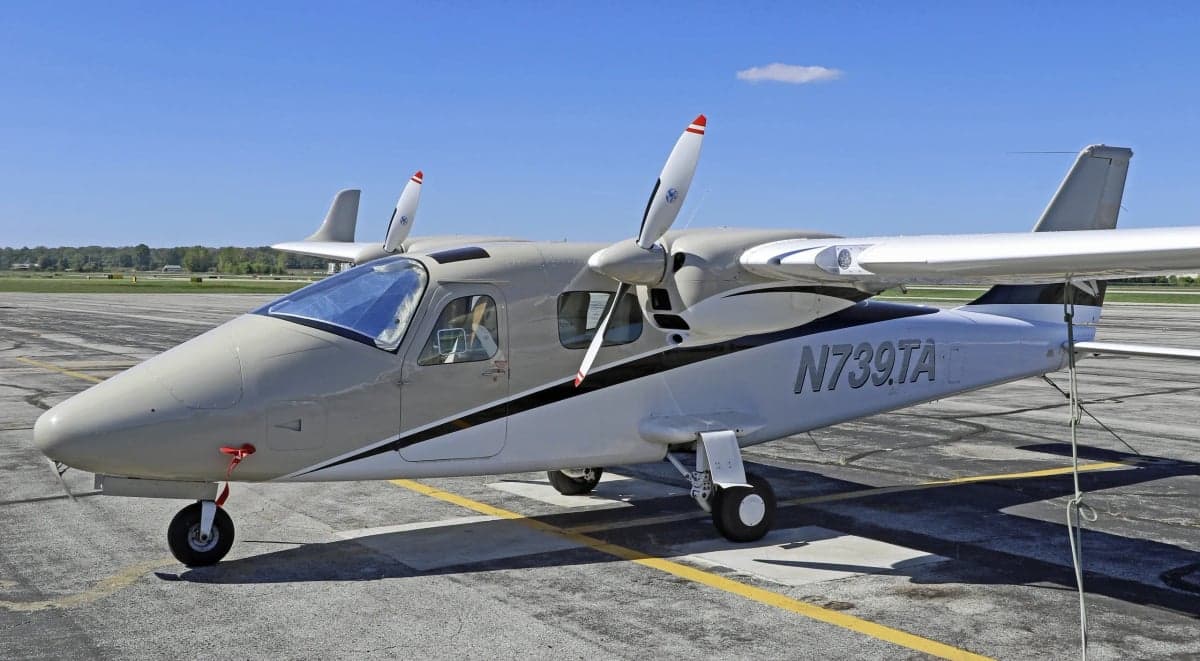 A grey and white twin-engine aircraft is parked on the tarmac.