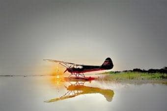 A float plane sits on the water at sunset.