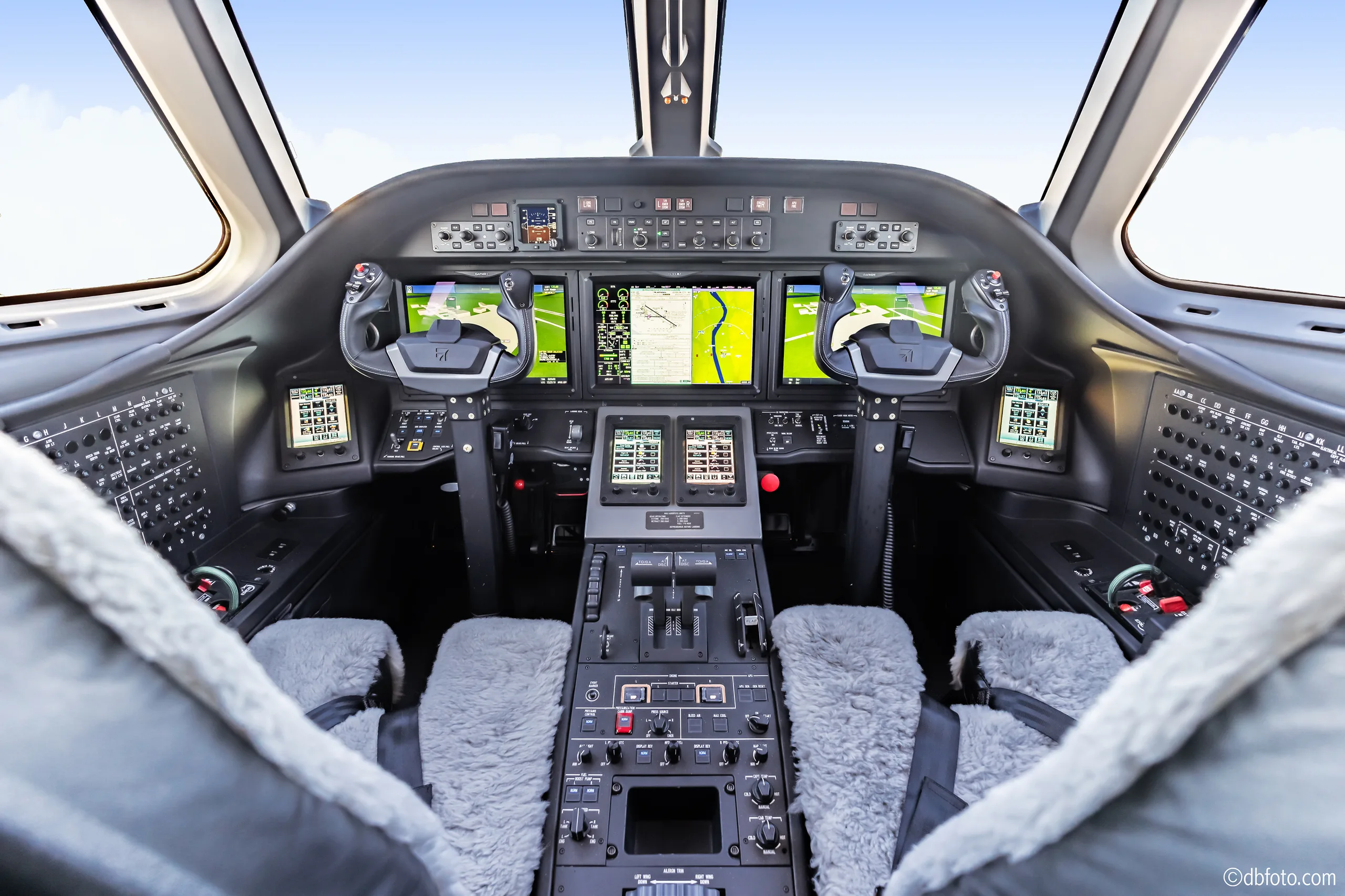 The modern cockpit of the business jet features multiple digital displays and a central control panel.