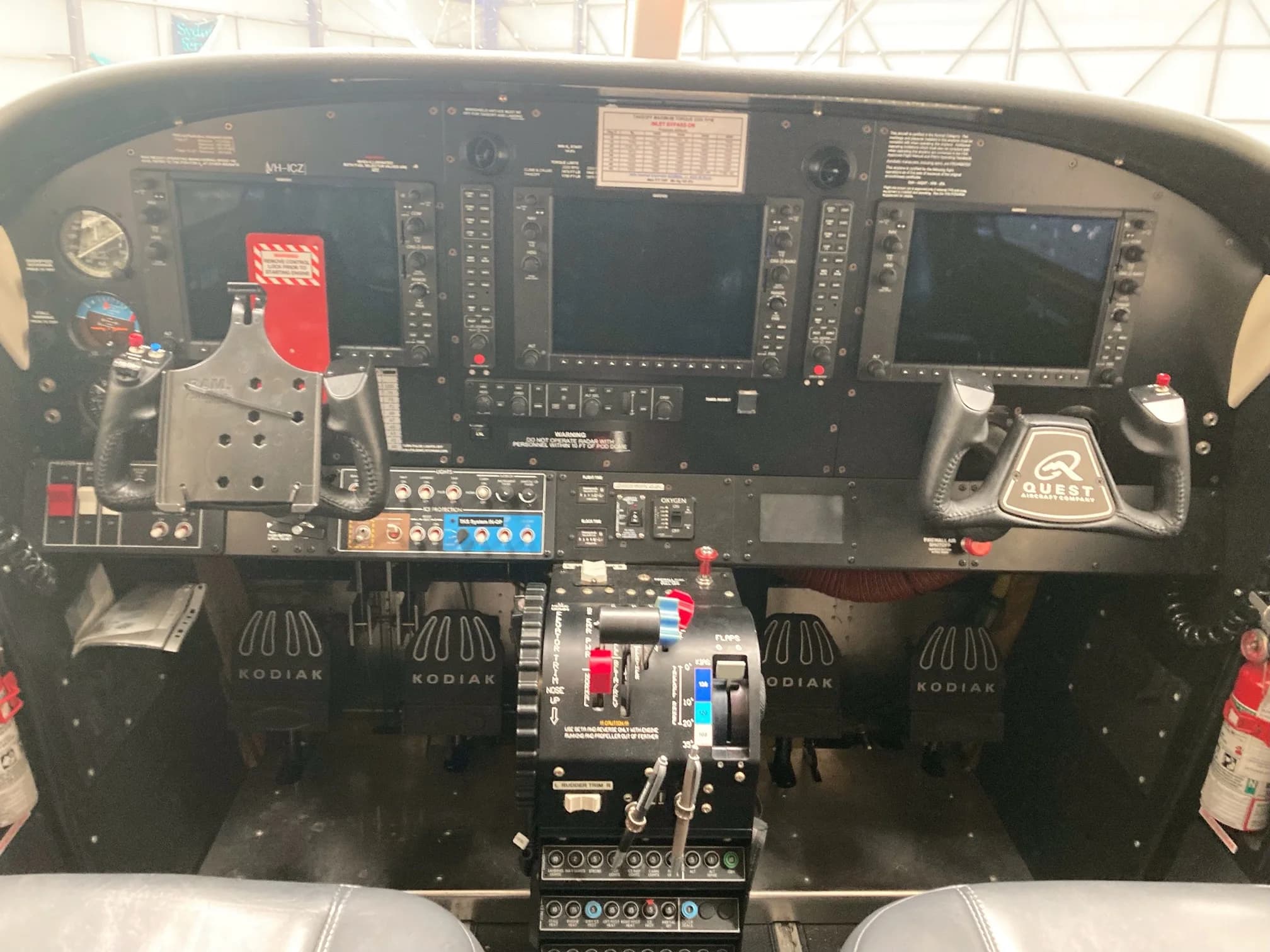 The cockpit of a Quest Kodiak 100 aircraft, showing the instrument panel with two large screens, yokes, and central throttle quadrant.