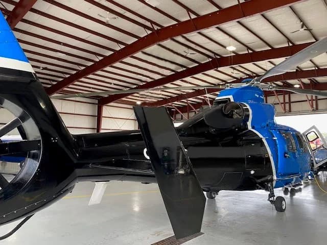 Rear view of the blue and black Airbus AS365 N3 Dauphin helicopter inside a hangar.