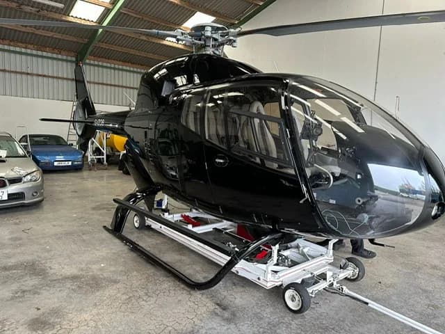 G-IZOB helicopter on a wheeled platform inside a hangar.