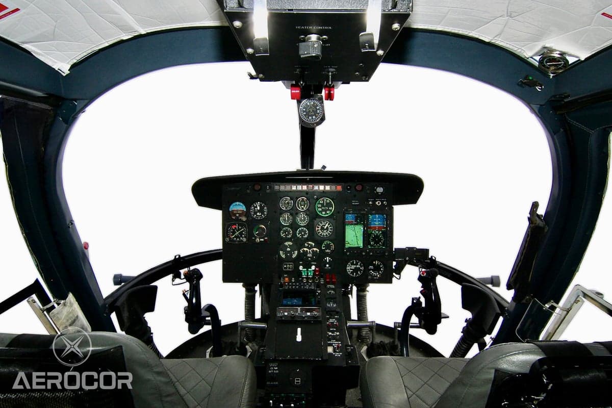 View of a helicopter cockpit with a detailed instrument panel and controls.