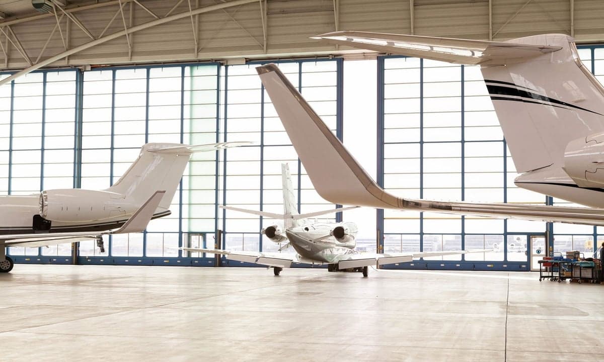 Several business jets parked inside a hangar.