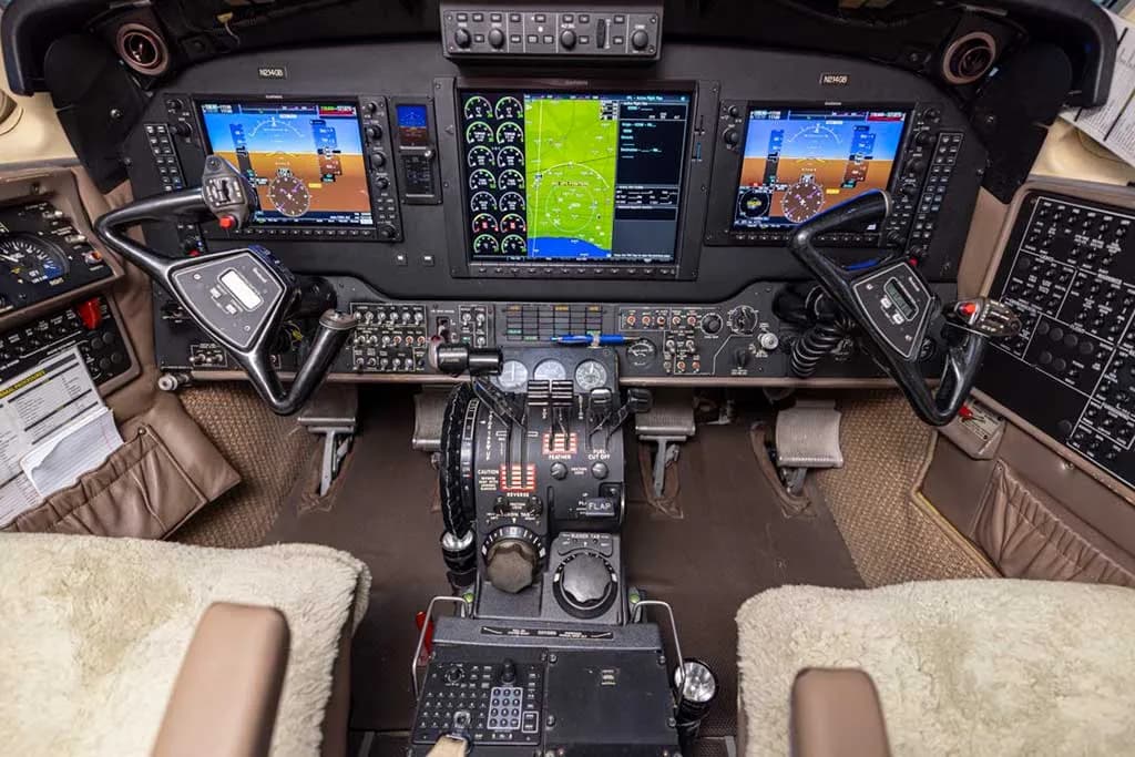 The aircraft cockpit features multiple digital displays, control yokes, and a central throttle quadrant.