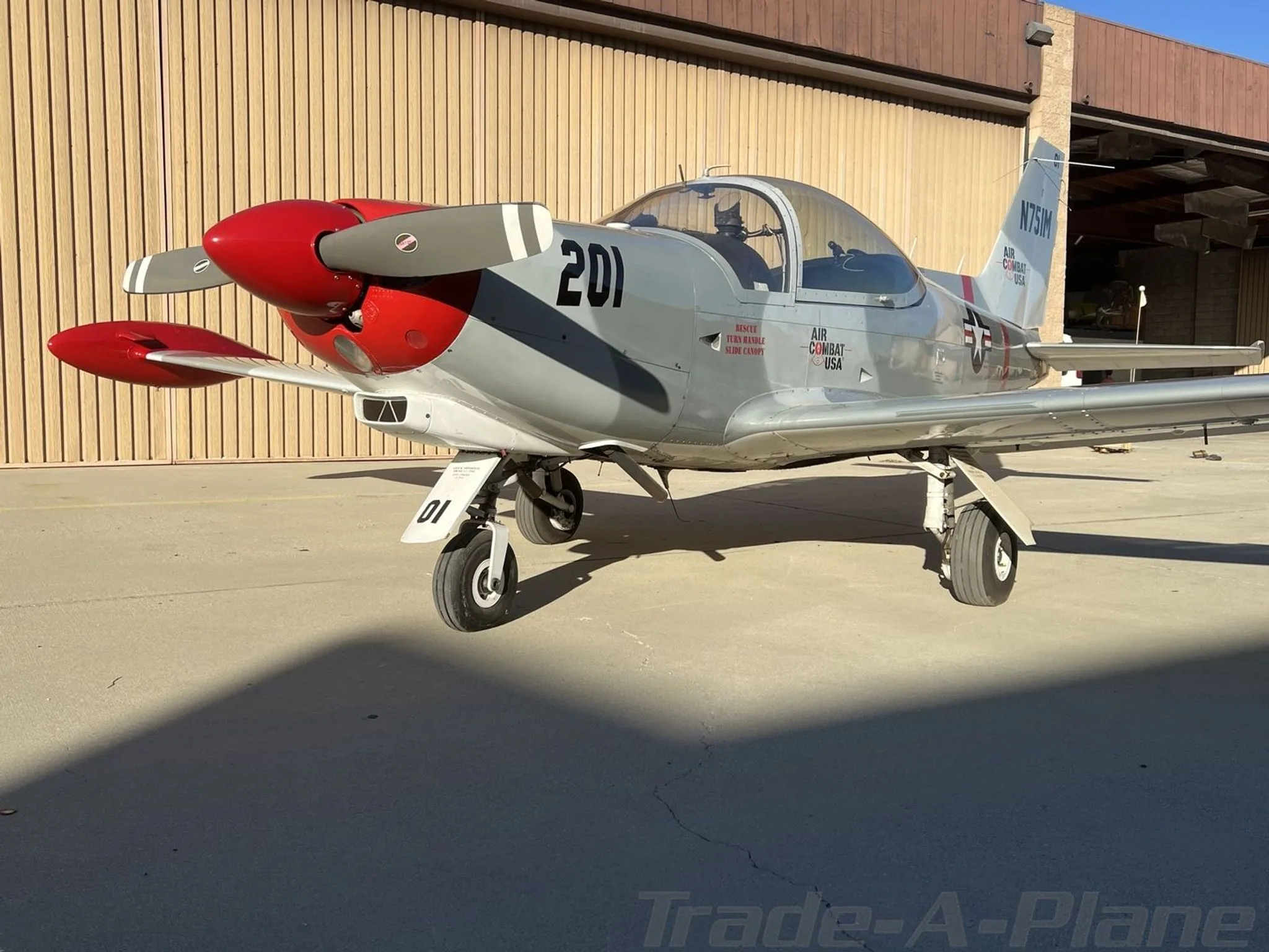 A front-right view of the grey and red Air Combat USA aircraft '201' with its propeller visible.