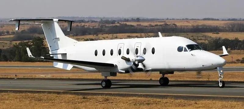A front side view of a white King Air aircraft on the runway.