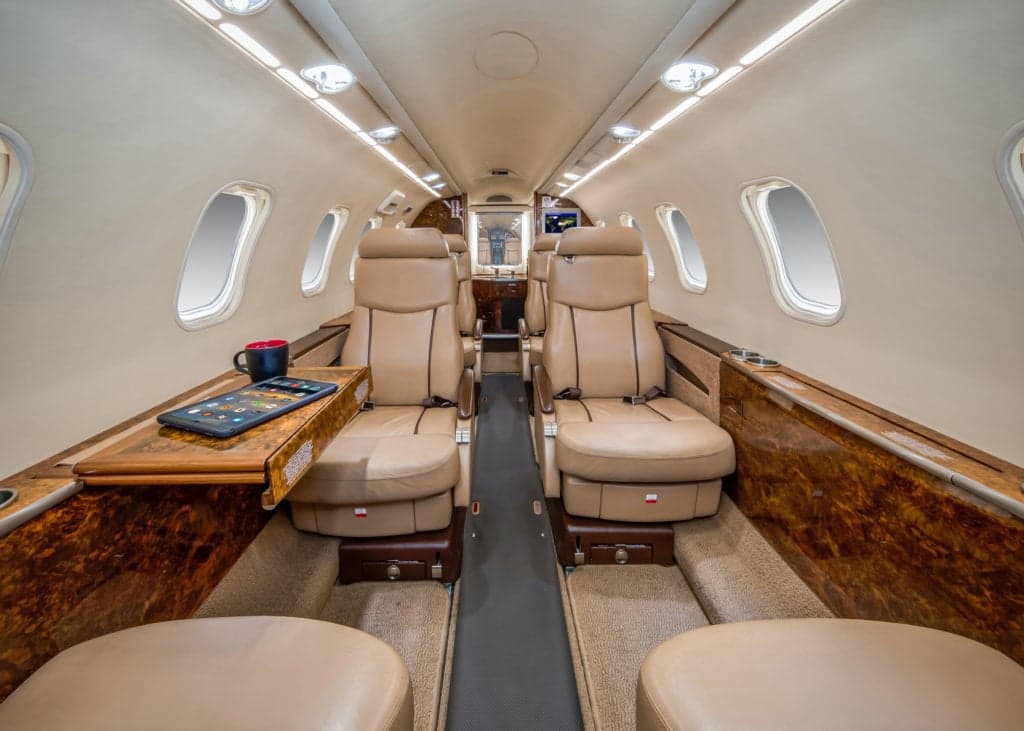 View of the aircraft cabin showing the cockpit entrance and a tan leather seat.