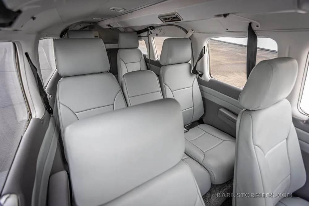 The light gray leather rear cabin seats of a small aircraft, viewed from the back.