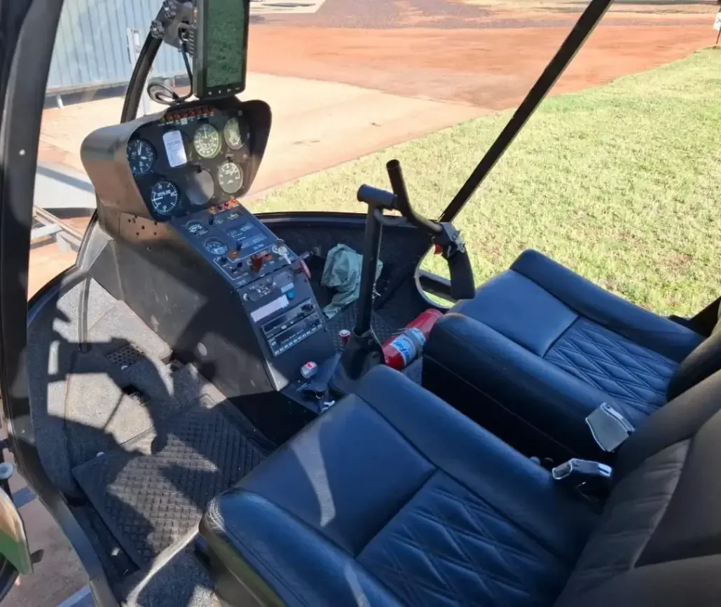 Cockpit view of the helicopter's instrument panel and black leather seats.