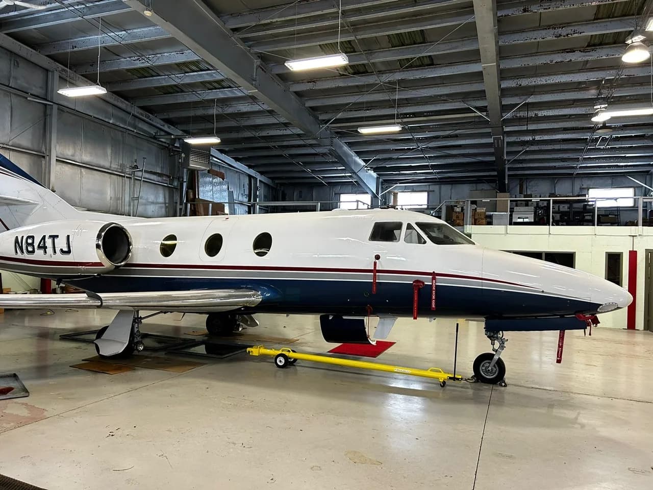 Side view of the aircraft N84TJ in a hangar.