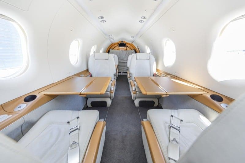 The interior of a Pilatus PC-12 aircraft with white leather seats.