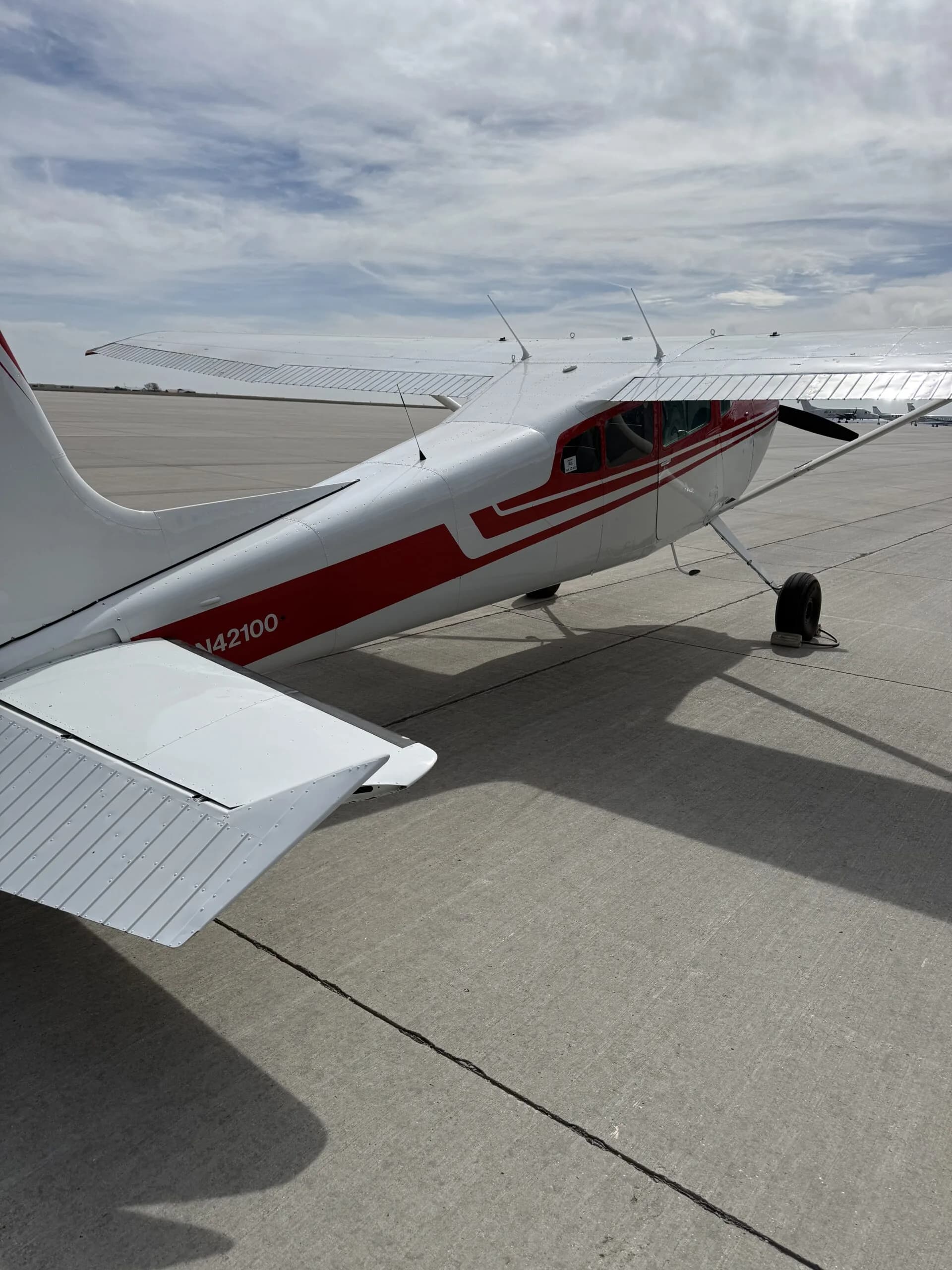 Rear-right view of a white and red Cessna 172 parked on an airport tarmac, showing the N42100 registration.