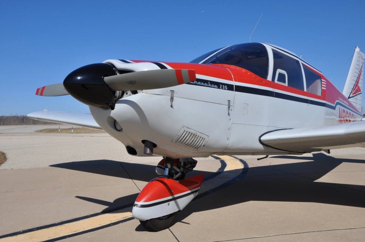 Close-up of the nose and propeller of a Cherokee 180 aircraft.