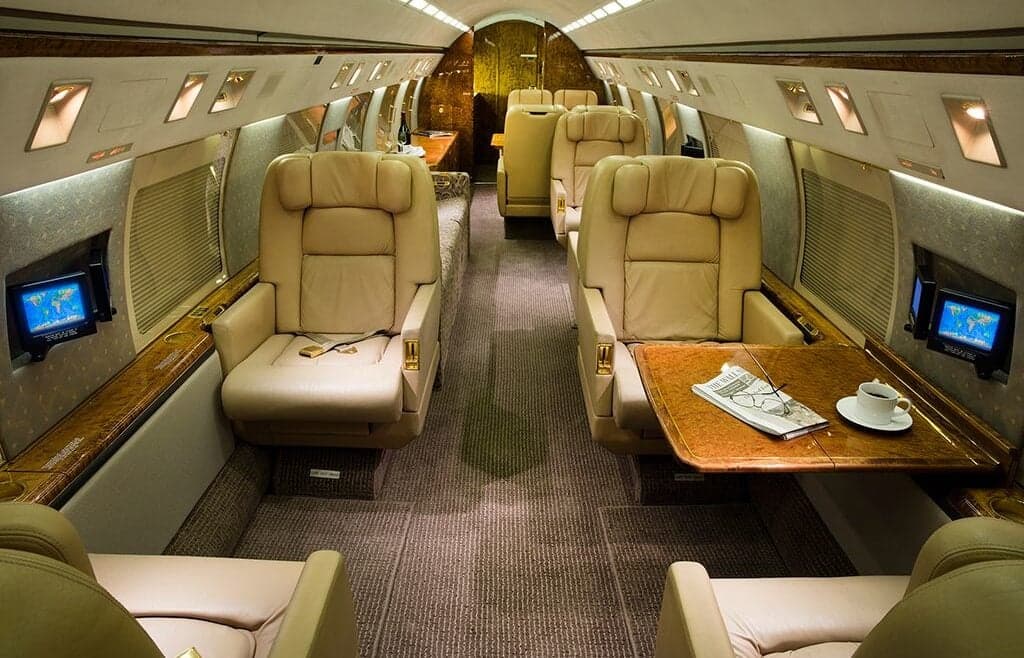 Interior of the aircraft featuring leather seats, tables, and monitors.