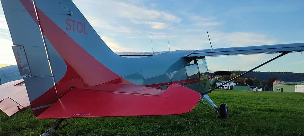 A close-up view of the red and gray tail of the N346X aircraft, with "STOL" visible, parked on grass.