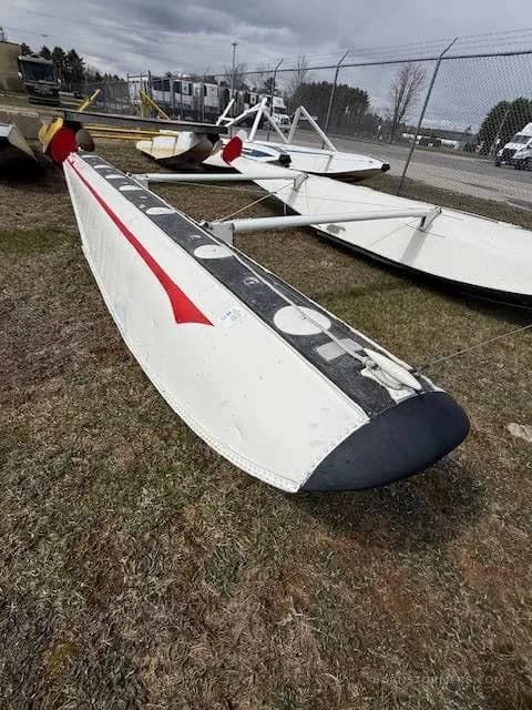 A close-up view of a white aircraft float with a red stripe on the grass.