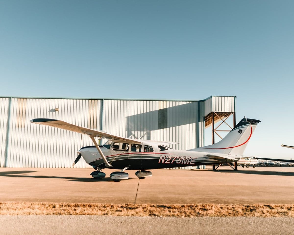 Side view of Cessna 206 Turbo Stationair TC aircraft N273ME parked in front of a hangar.