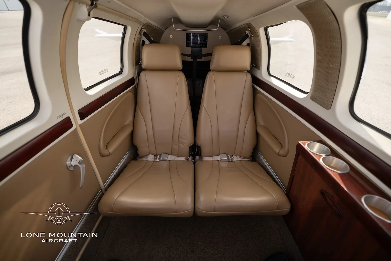 A view of the aircraft's tan leather rear cabin seats with seatbelts, looking towards the front.