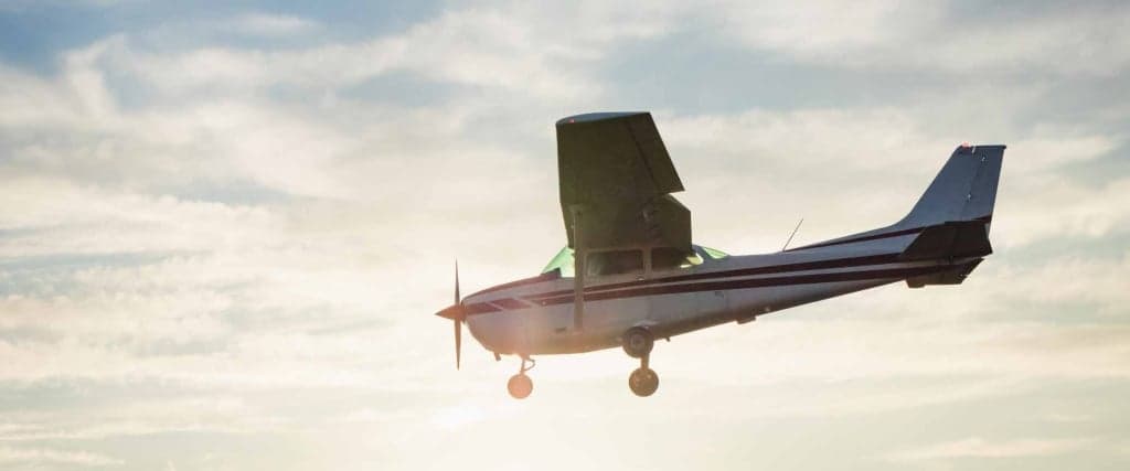 A small single-engine airplane in flight against a cloudy sky.