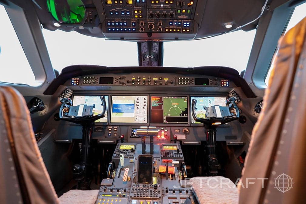 The modern glass cockpit of a Gulfstream G550 business jet with multiple display screens and controls.