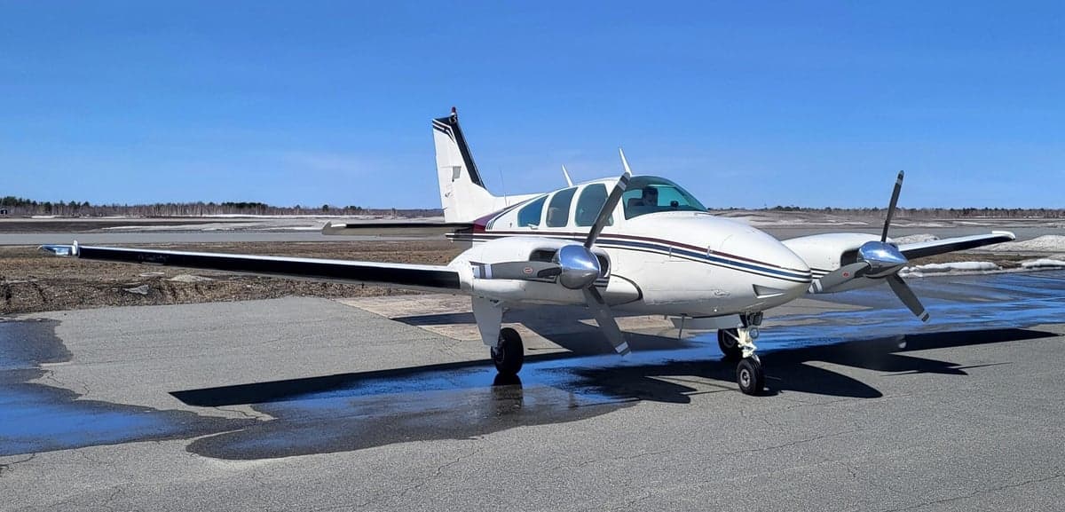 A Beechcraft Baron sits on the tarmac on a sunny day.