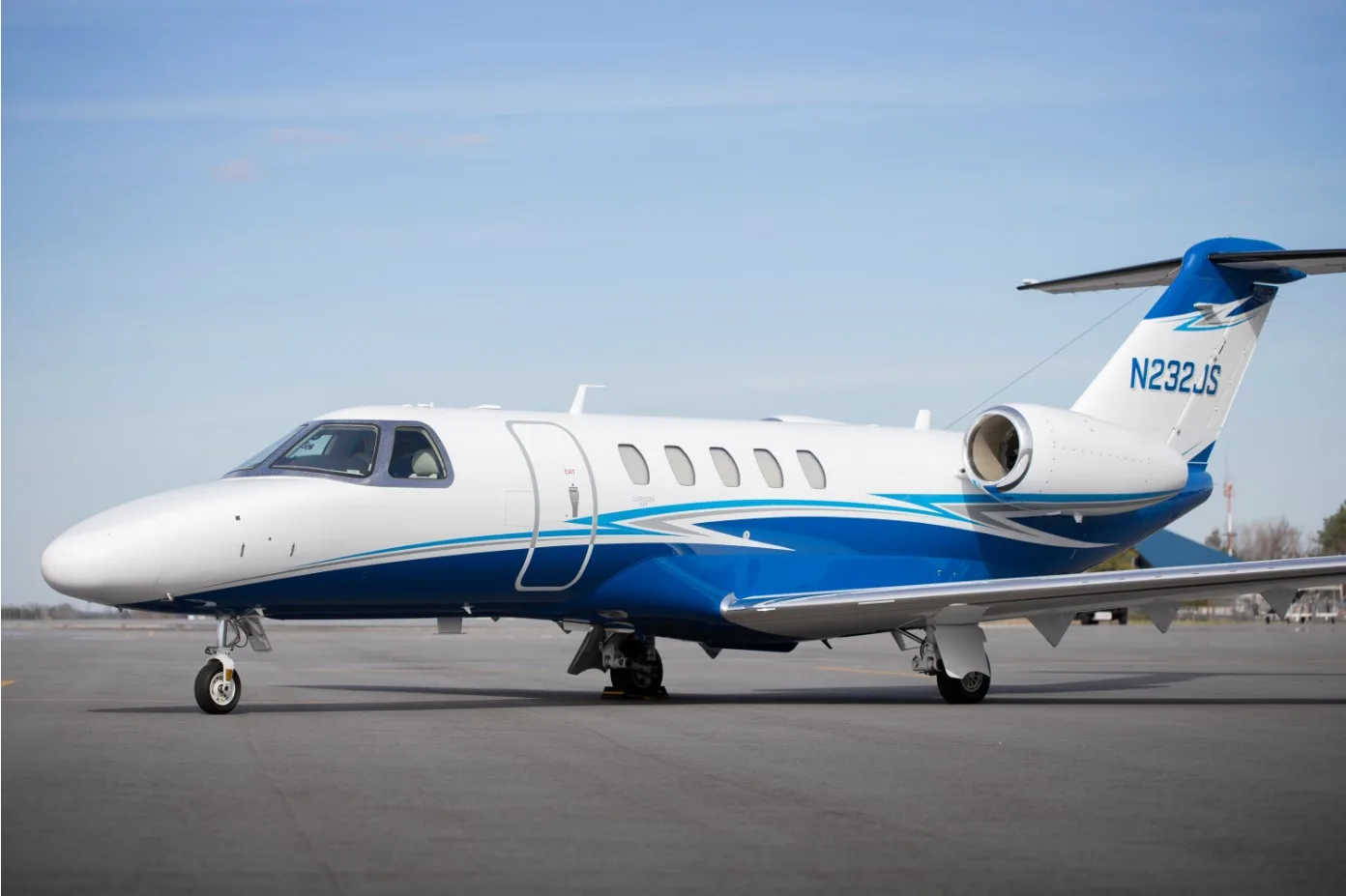 A side view of the white and blue N232JS aircraft on the tarmac.